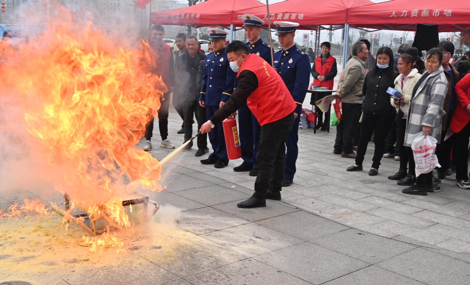 图为志愿者向现场群众演示灭火器的使用方法.jpg